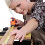 16950834 - a female carpenter measuring.